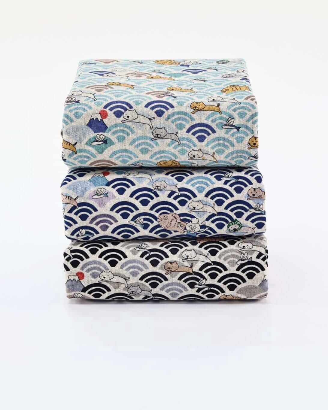 Trois coupons de tissu coton japonais pliés, motif vagues seigaiha avec chats et animaux kawaii, en coloris bleu clair, bleu marine et gris