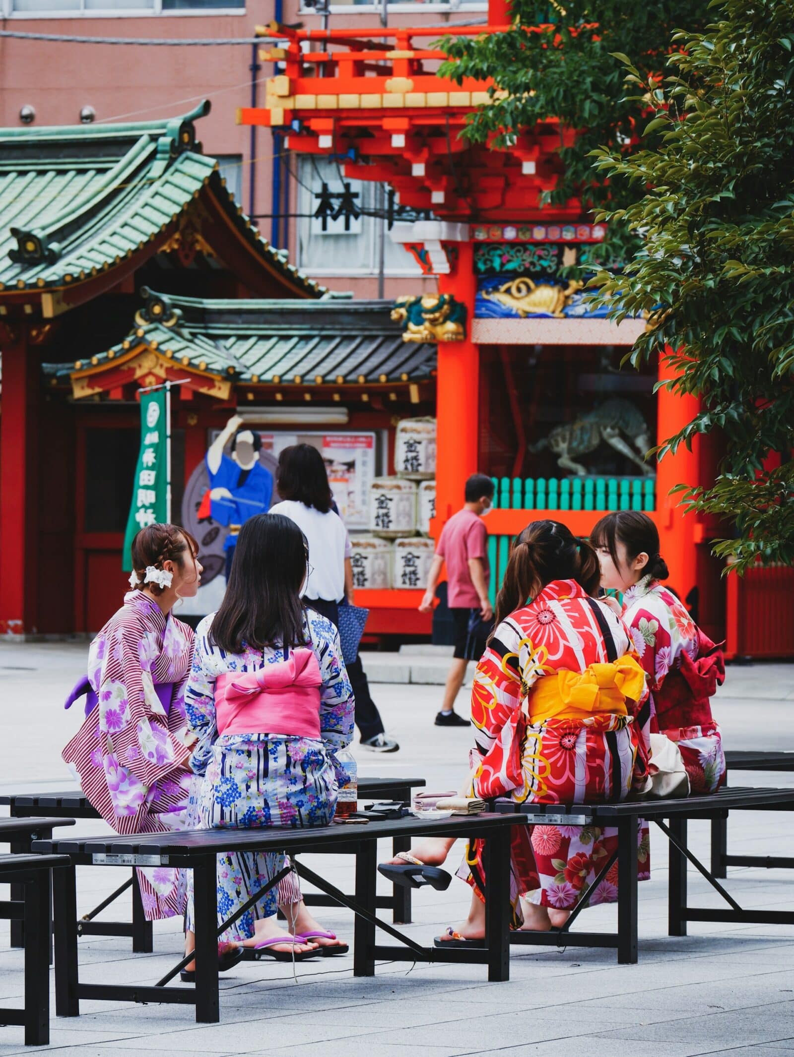Women in colorful yukata sitting near a shrine in Japan