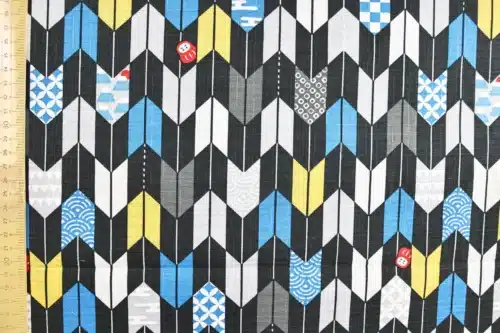 Japanese arrow feather yagasuri fabric graphic on a black background, flat with ruler