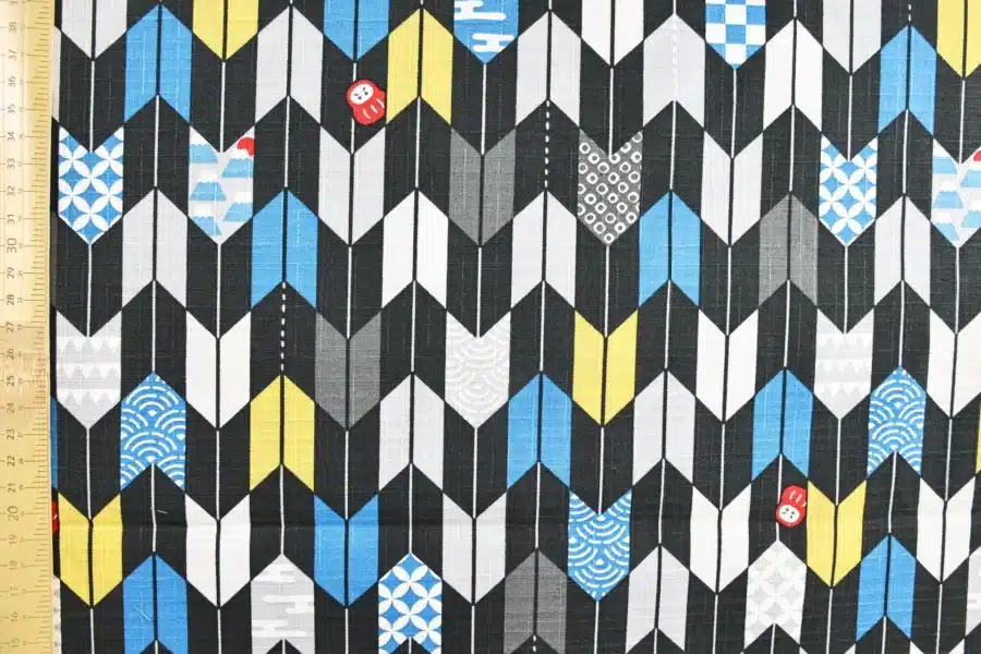 Japanese arrow feather yagasuri fabric graphic on a black background, flat with ruler