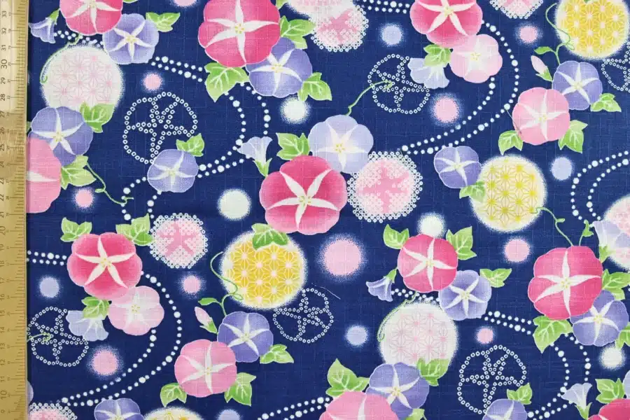 Japanese morning glory asagao fabric with pink and mauve flowers on a navy blue background, flat with ruler