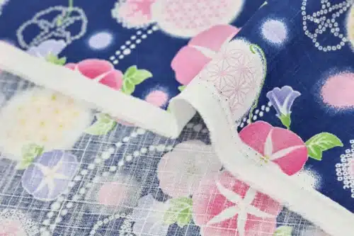 Japanese morning glory asagao fabric with pink and mauve flowers on a navy blue background, fold with selvedge and reverse side
