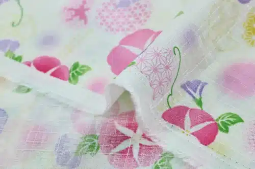 Japanese morning glory asagao fabric with pink and mauve flowers on an off-white background, fold with selvedge and reverse side